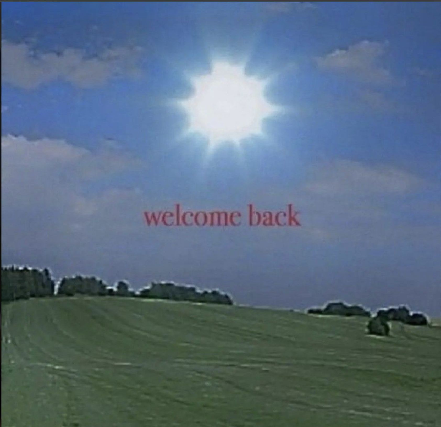 A bright sun above a green field, with the words welcome back across the sky.